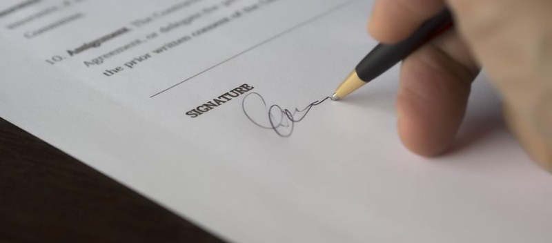 Une main signe un document au stylo.