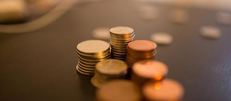 Quelques piles de pièces de monnaie posées sur une table sombre.