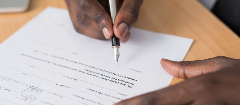 Une main remplit un formulaire au stylo, vue de près.
