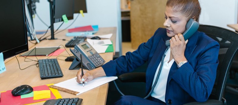 Une personne téléphone à son bureau tout en prenant des notes.